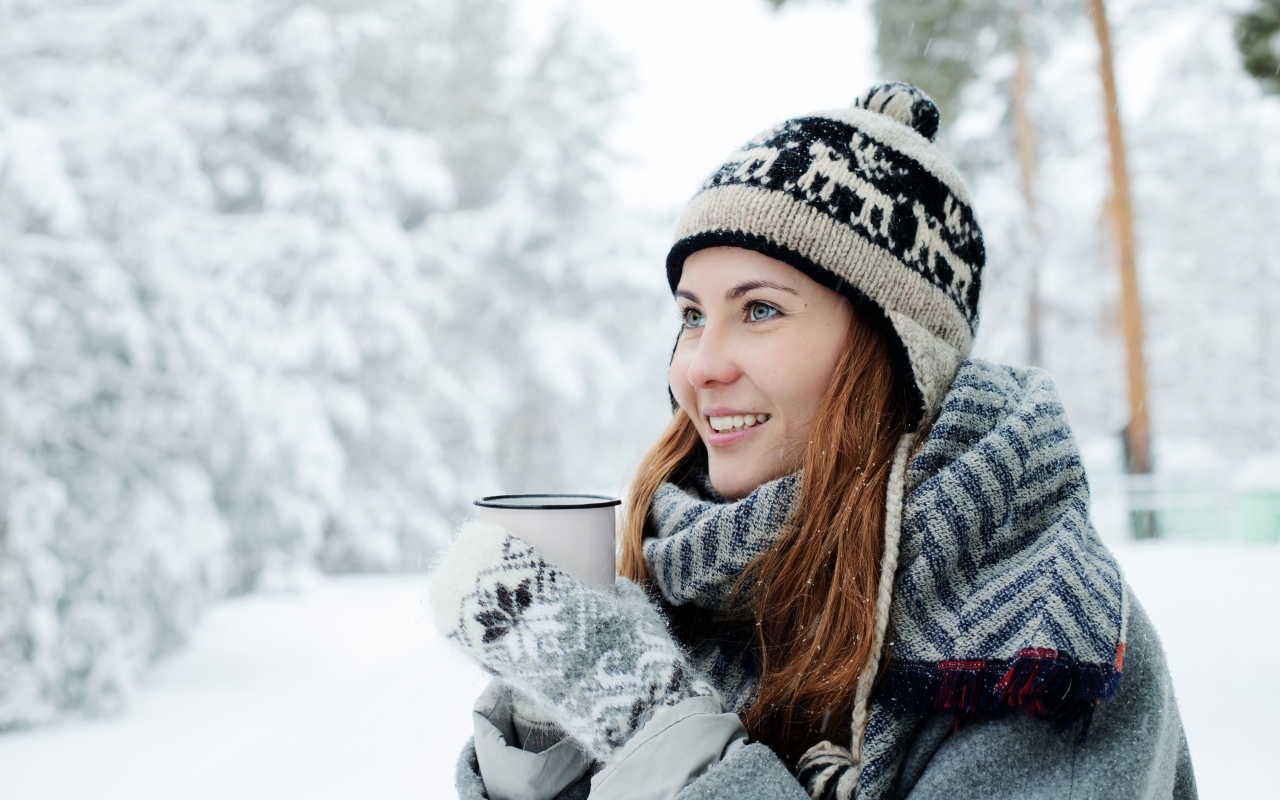 Улыбающаяся девушка с чашкой кофе зимой
