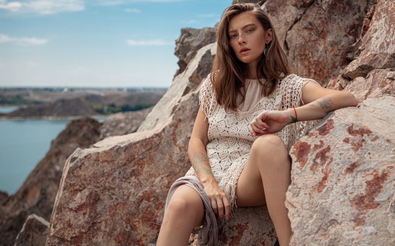 Молодая девушка сидит на камнях