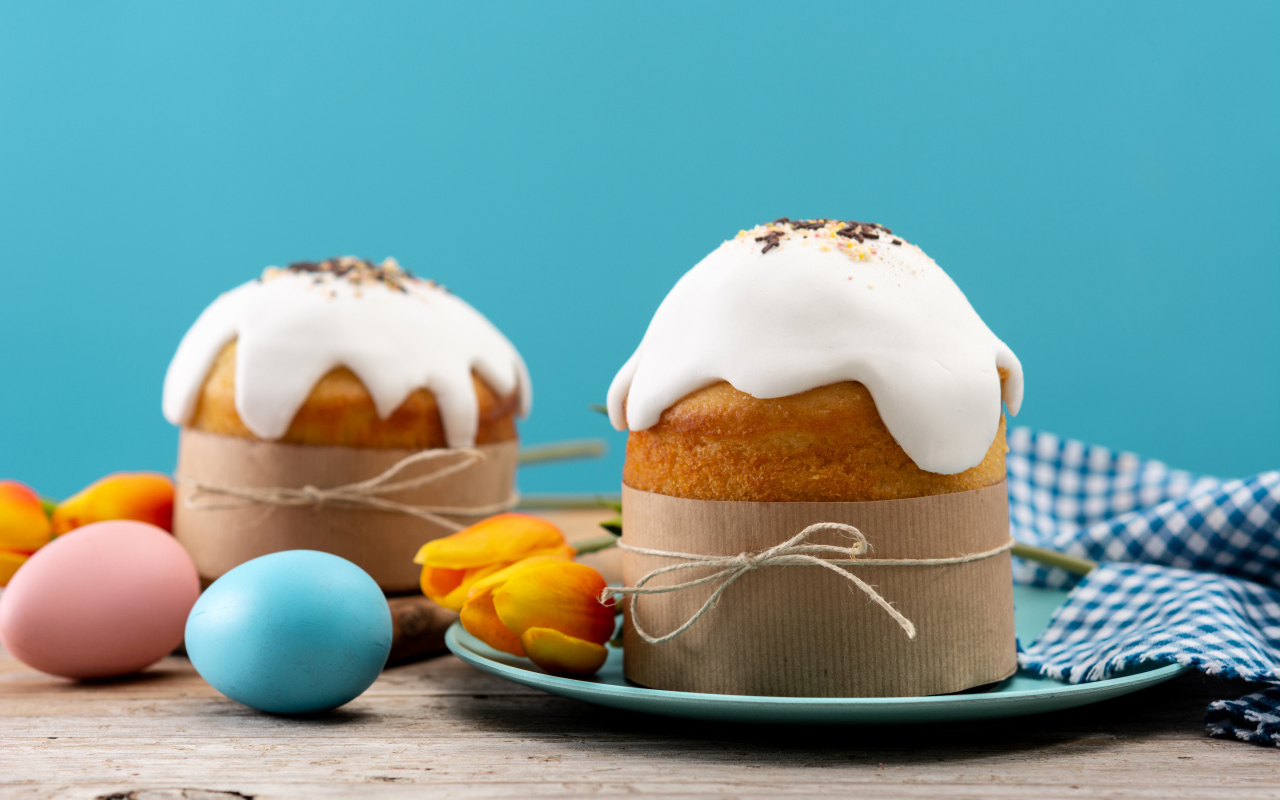 Пасхальные куличи с белой глазурью на столе с яйцами