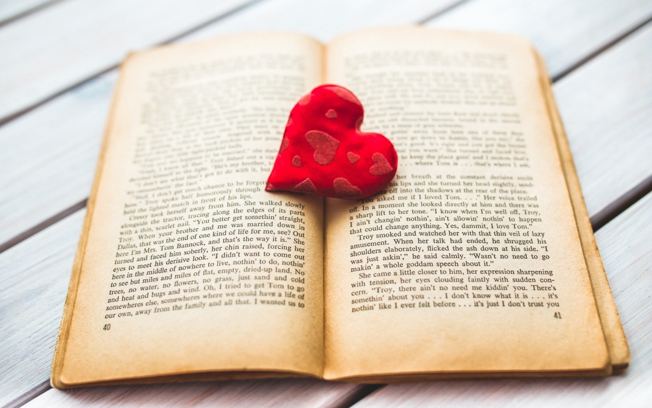 Маленькое красное сердце с книгой на столе