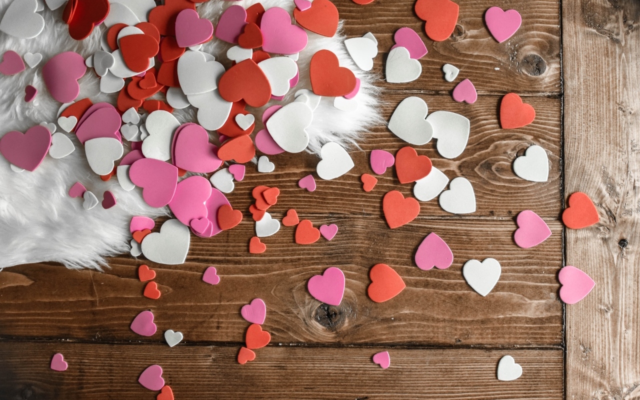 Много бумажных сердечек на деревянном полу