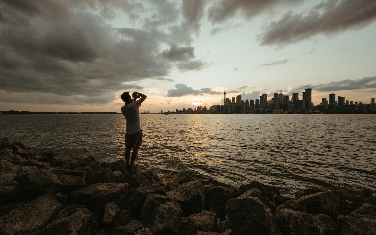 Мужчина делает фото города у моря