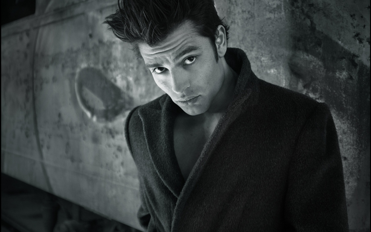 Красивый мужчина в черном пальто у стены