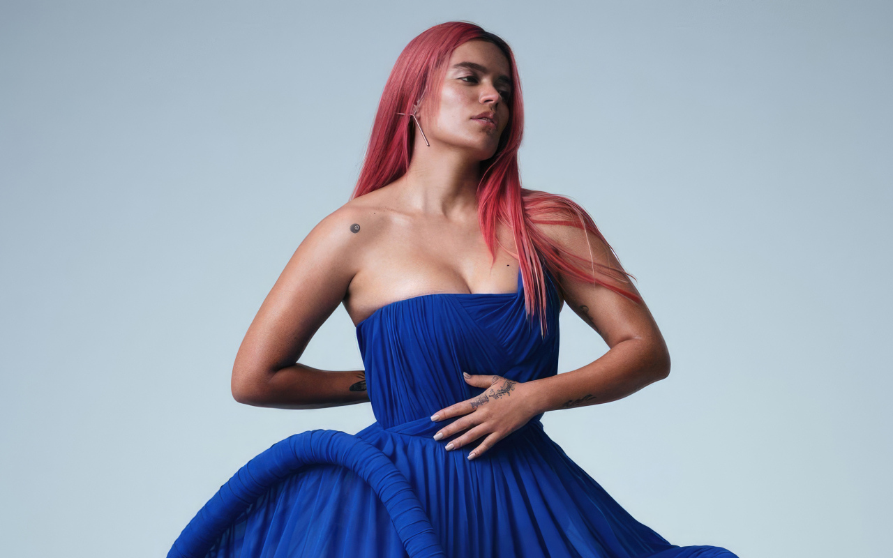 Певица Karol G в синем платье на сером фоне