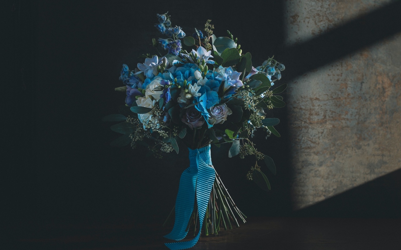 Красивый букет цветов с голубой лентой у стены