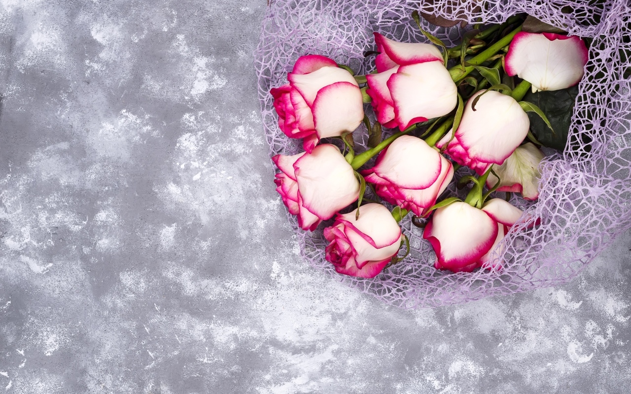 Красивый букет роз в упаковке на сером столе