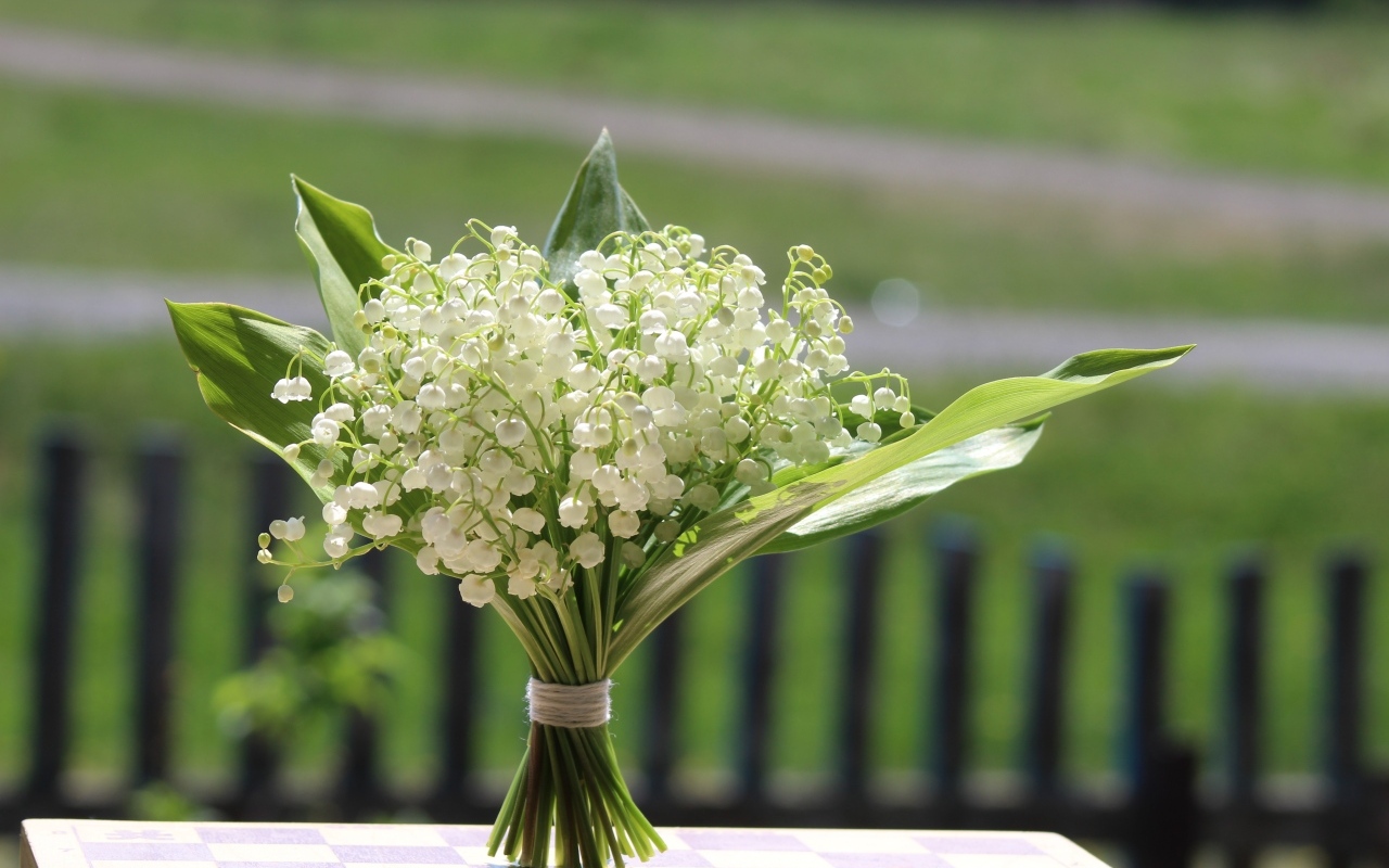 Красивый букет белых ландышей на столе в вазе