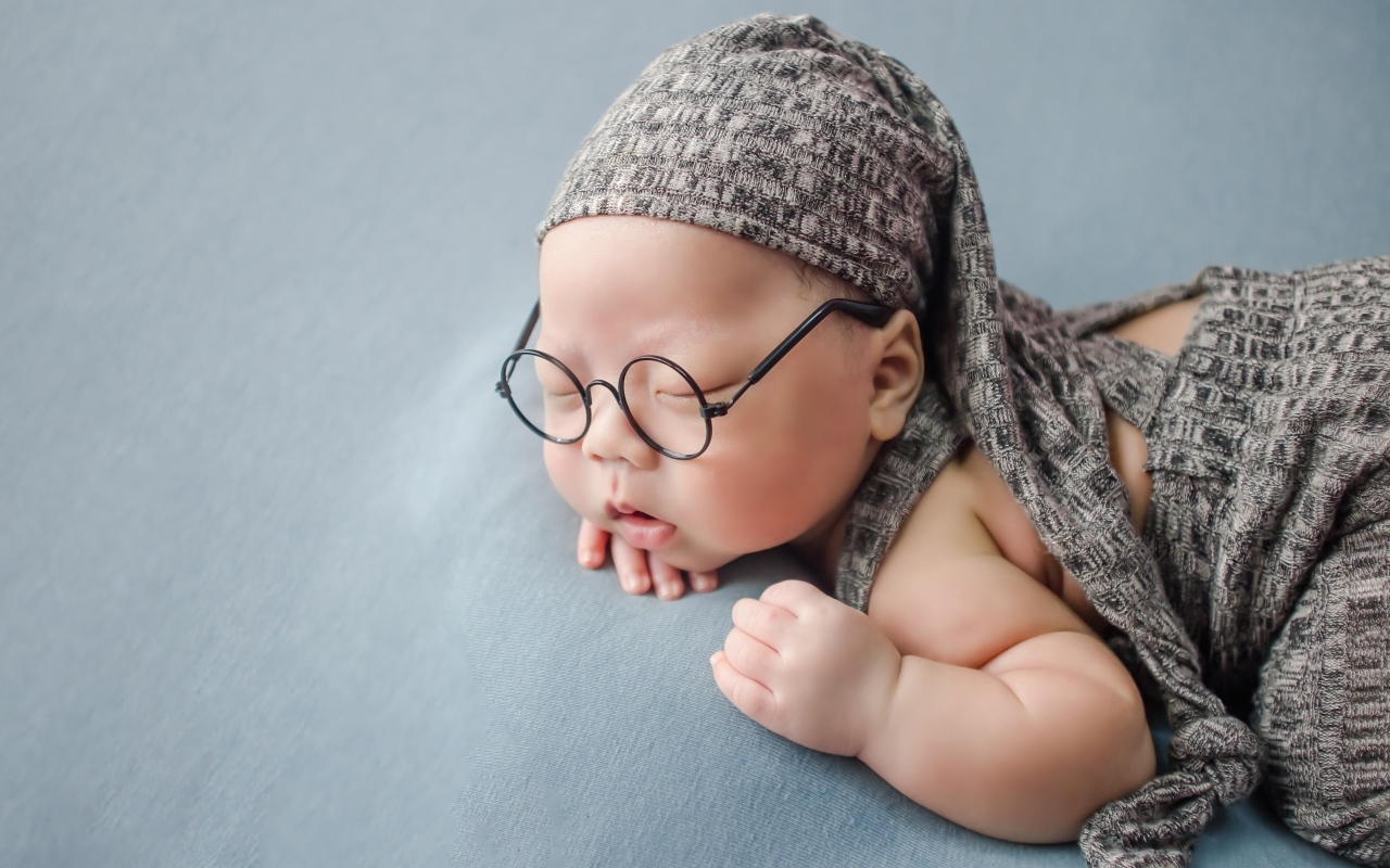 Забавный малыш в очках одет в серый костюм