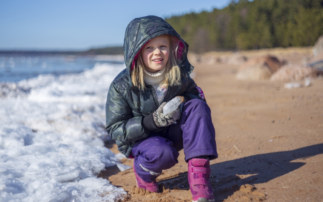 Девочка сидит у замерзшего озера 