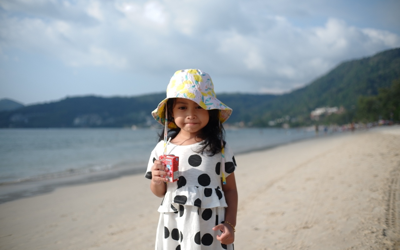 Девочка с соком в руках стоит на пляже