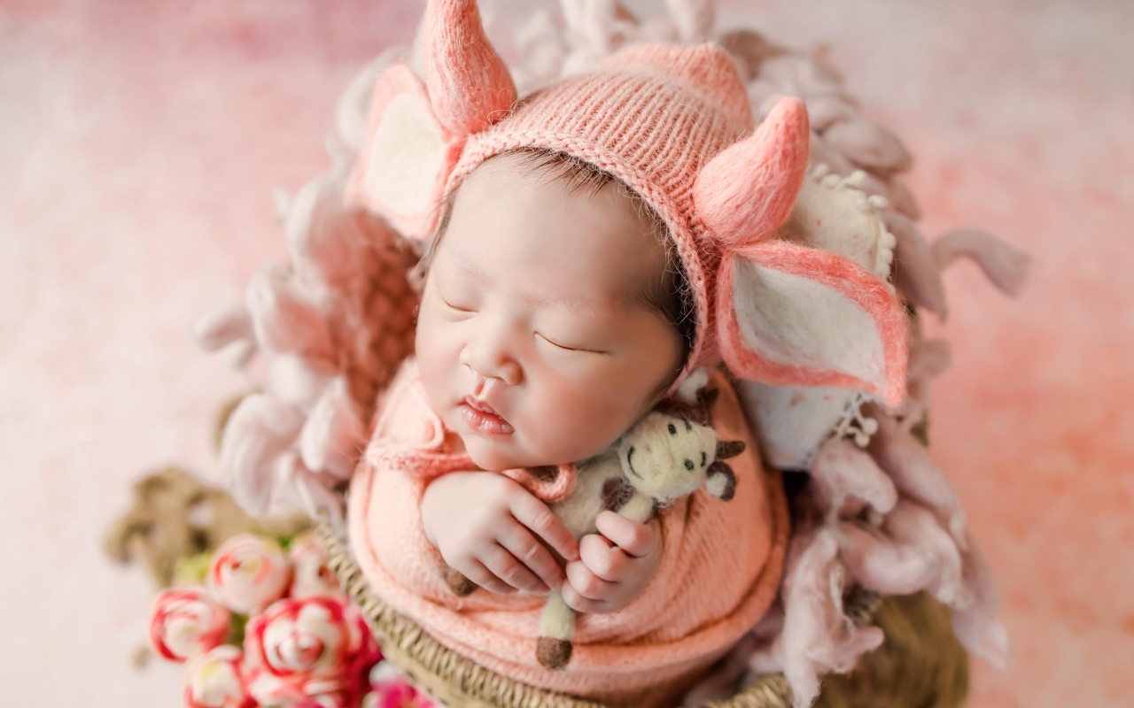 Маленький спящий новорожденный ребенок в шапке с рогами