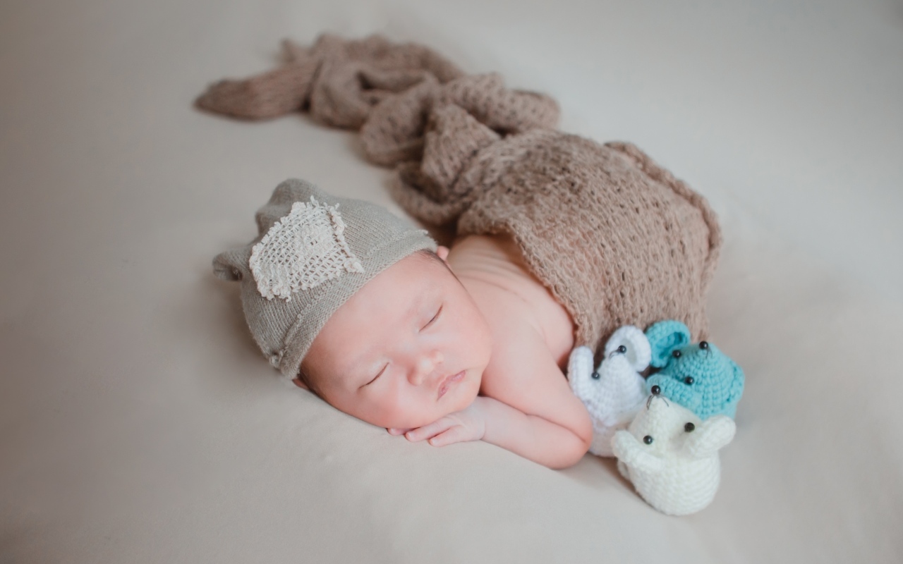 Новорожденный малыш спит на сером покрывале