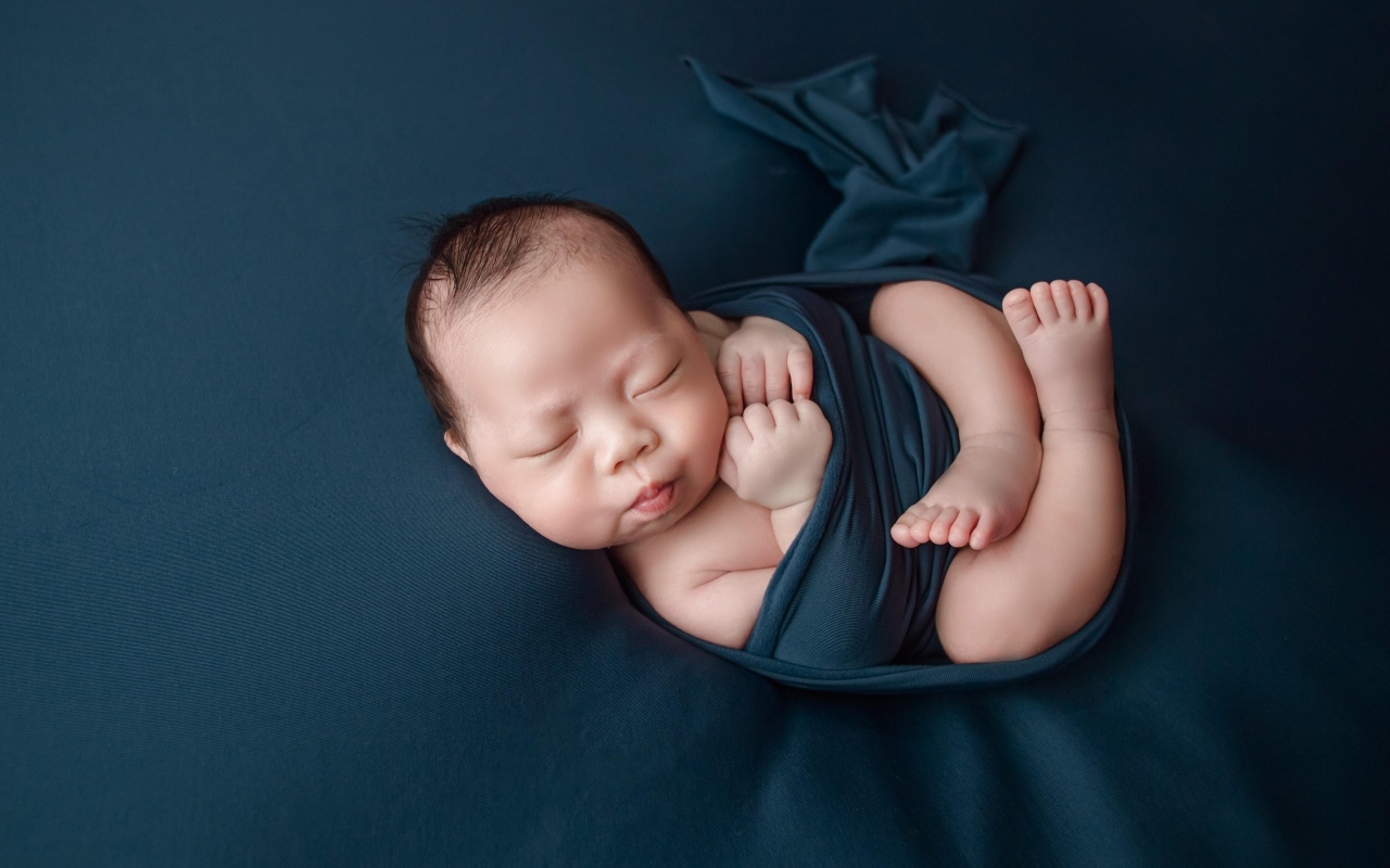 Новорожденный малыш в черном покрывале