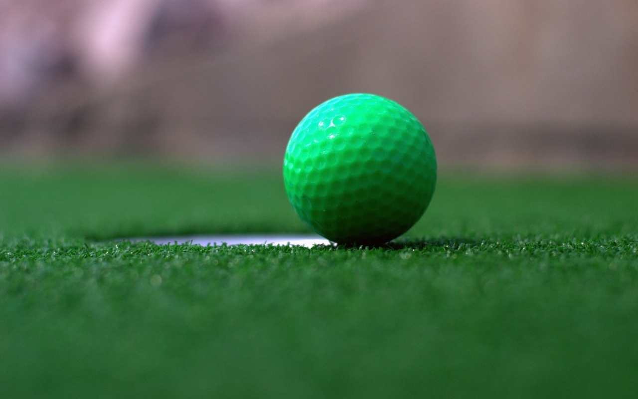 Зеленый мяч для игры в гольф на траве
