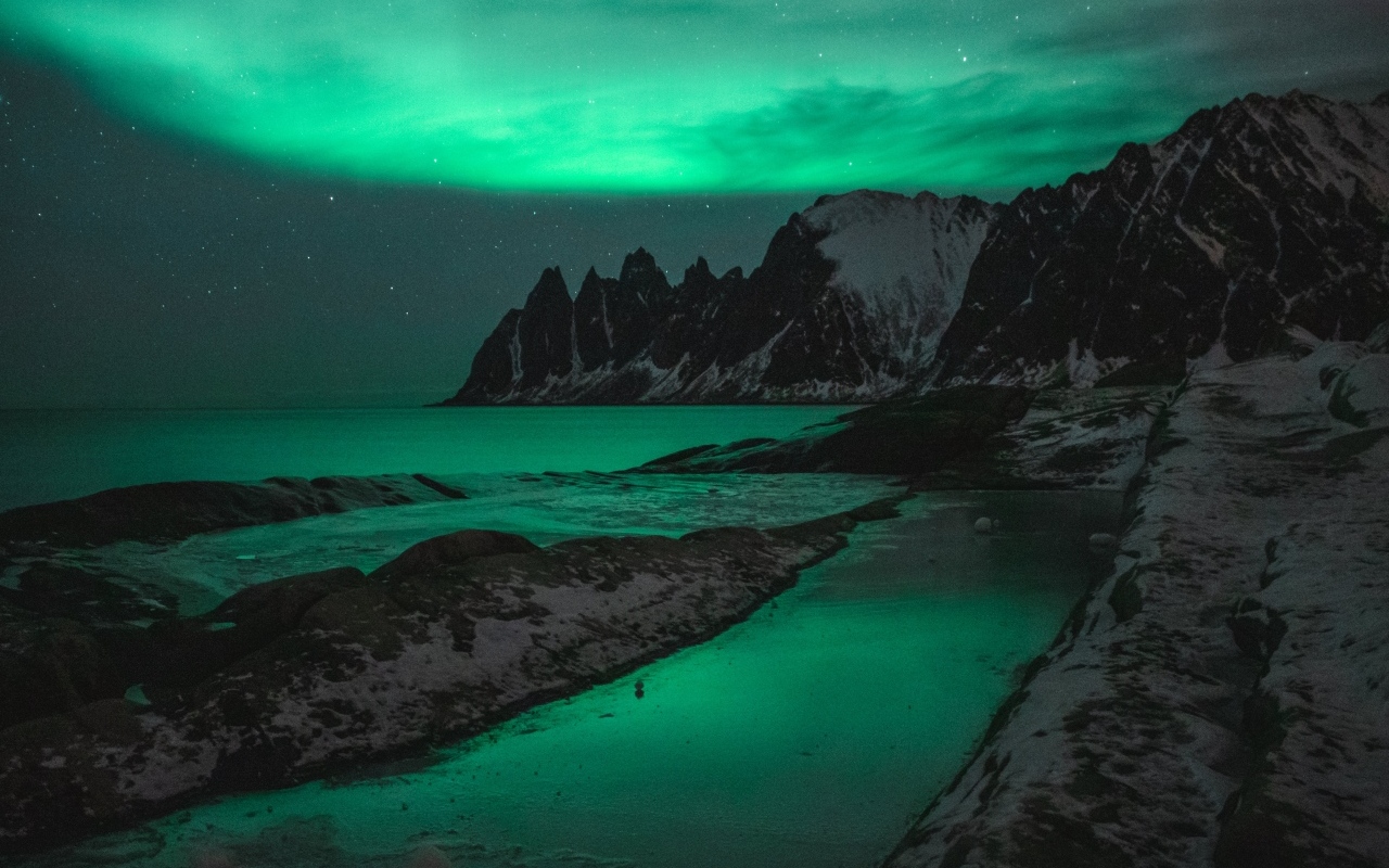 Зеленое полярное сияние над горами в Норвегии