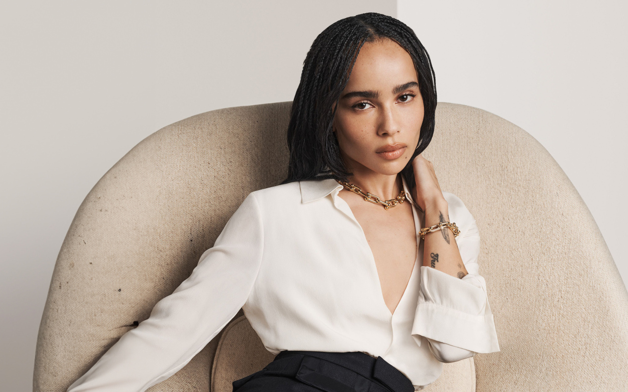 Актриса Зои Кравиц в белой рубашке сидит в кресле