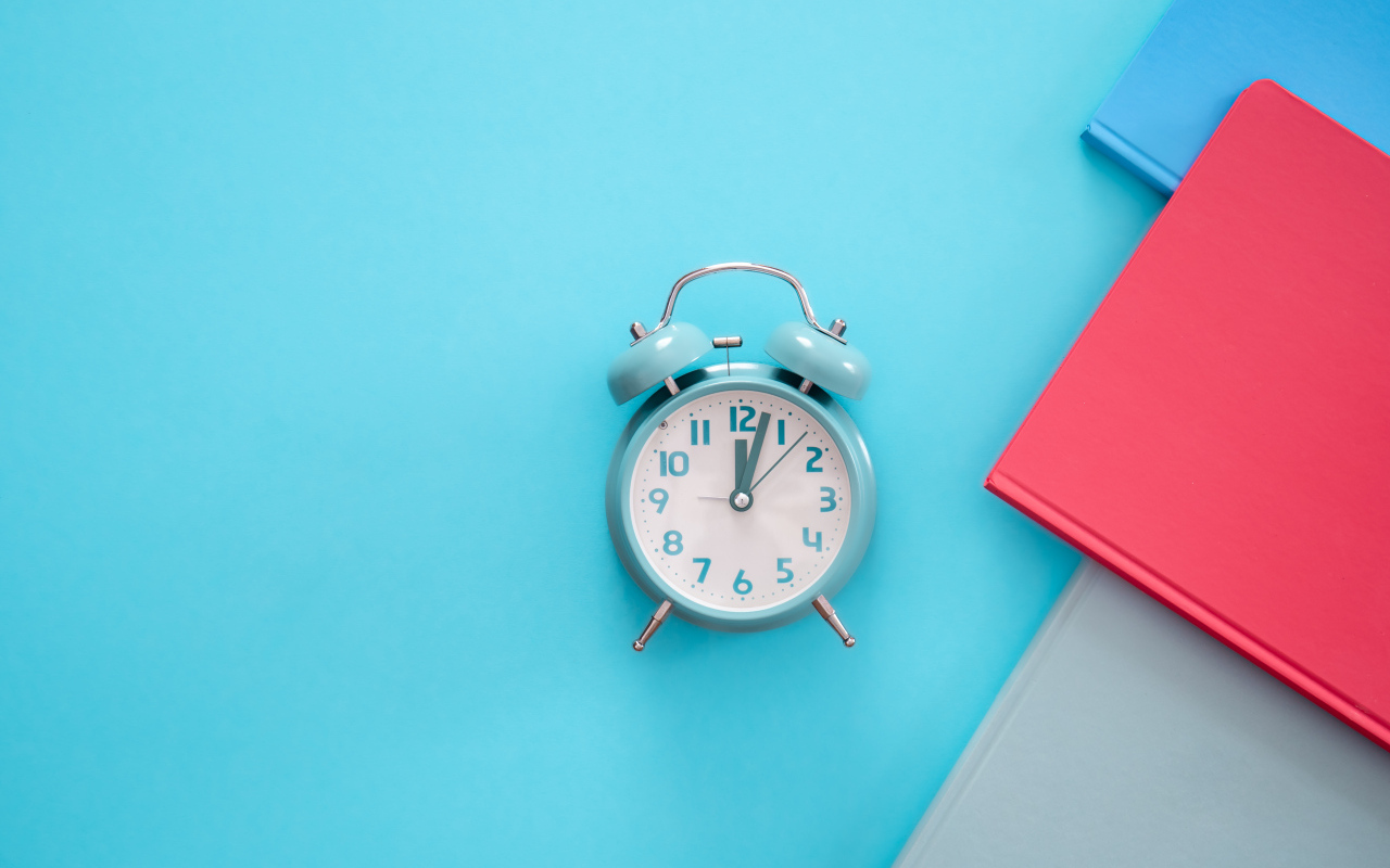 Будильник с книгами на голубом фоне