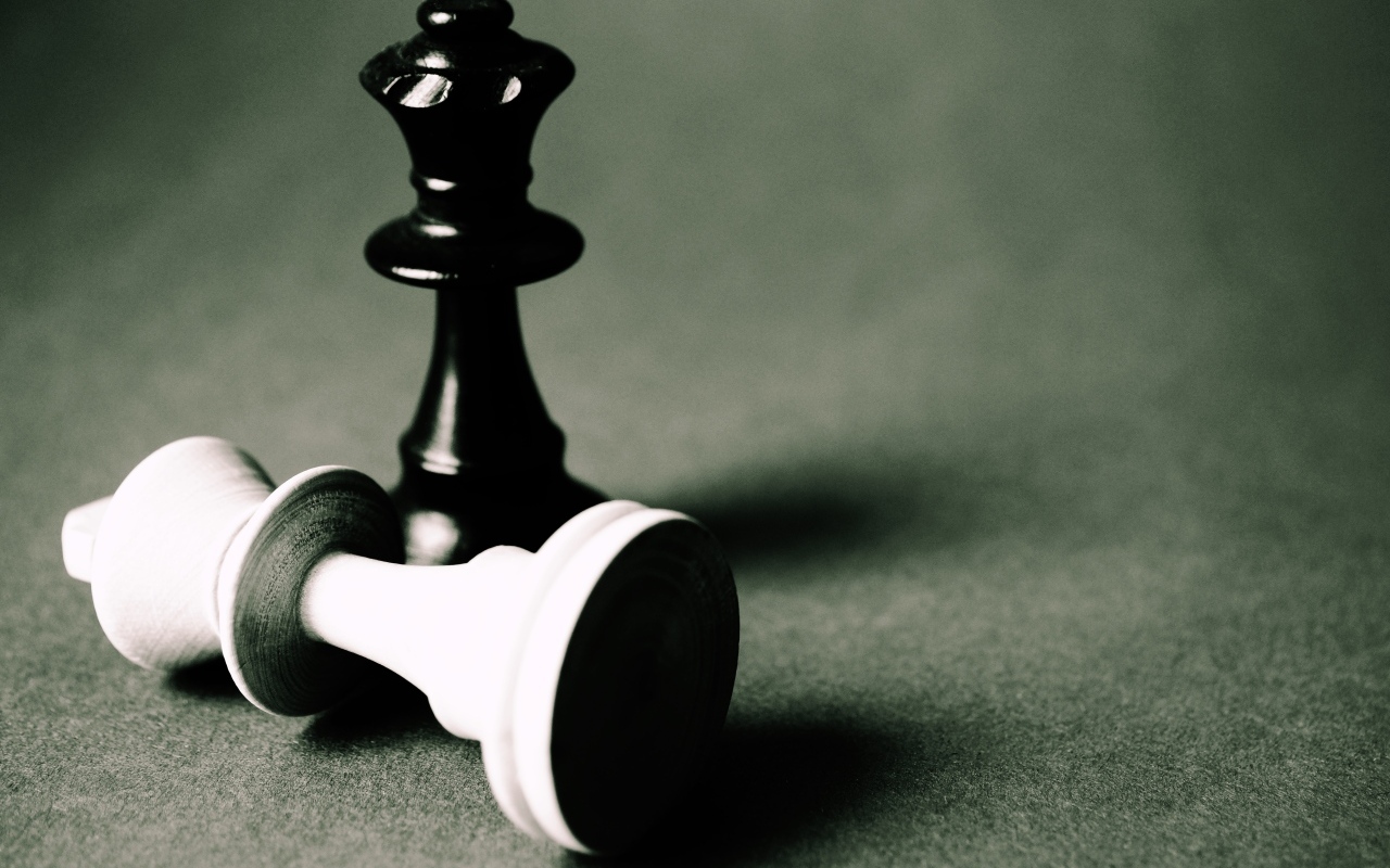 Черная и белая шахматные фигуры на сером столе