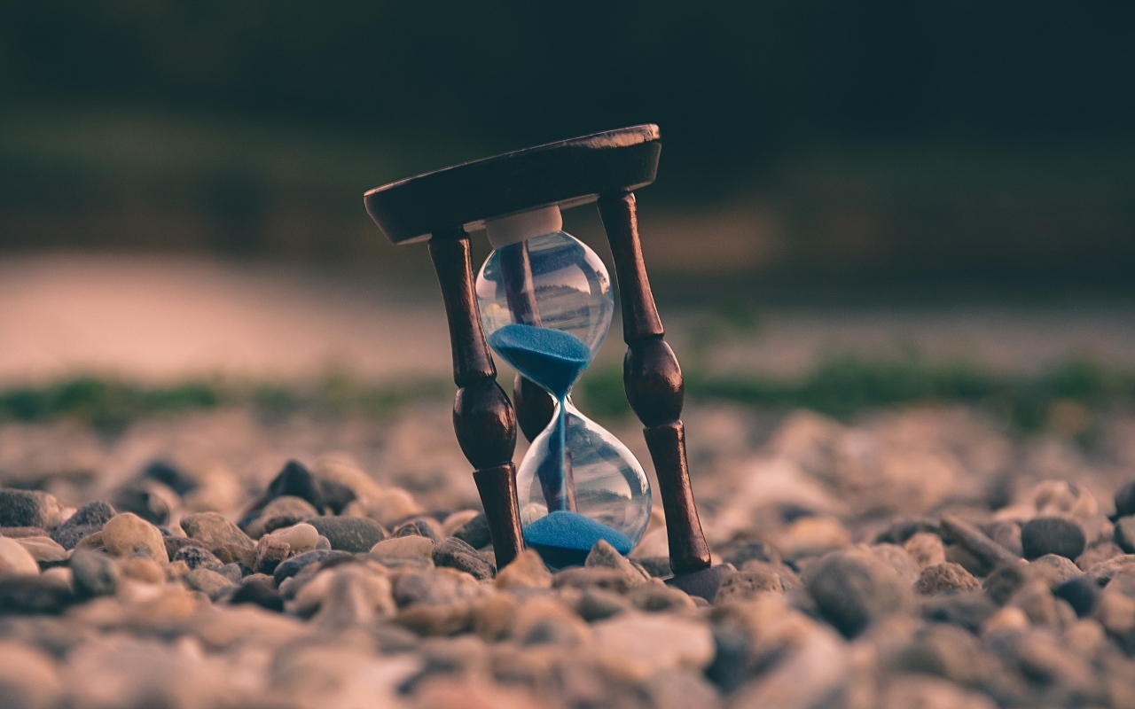 Песочные часы лежат на мелких камнях