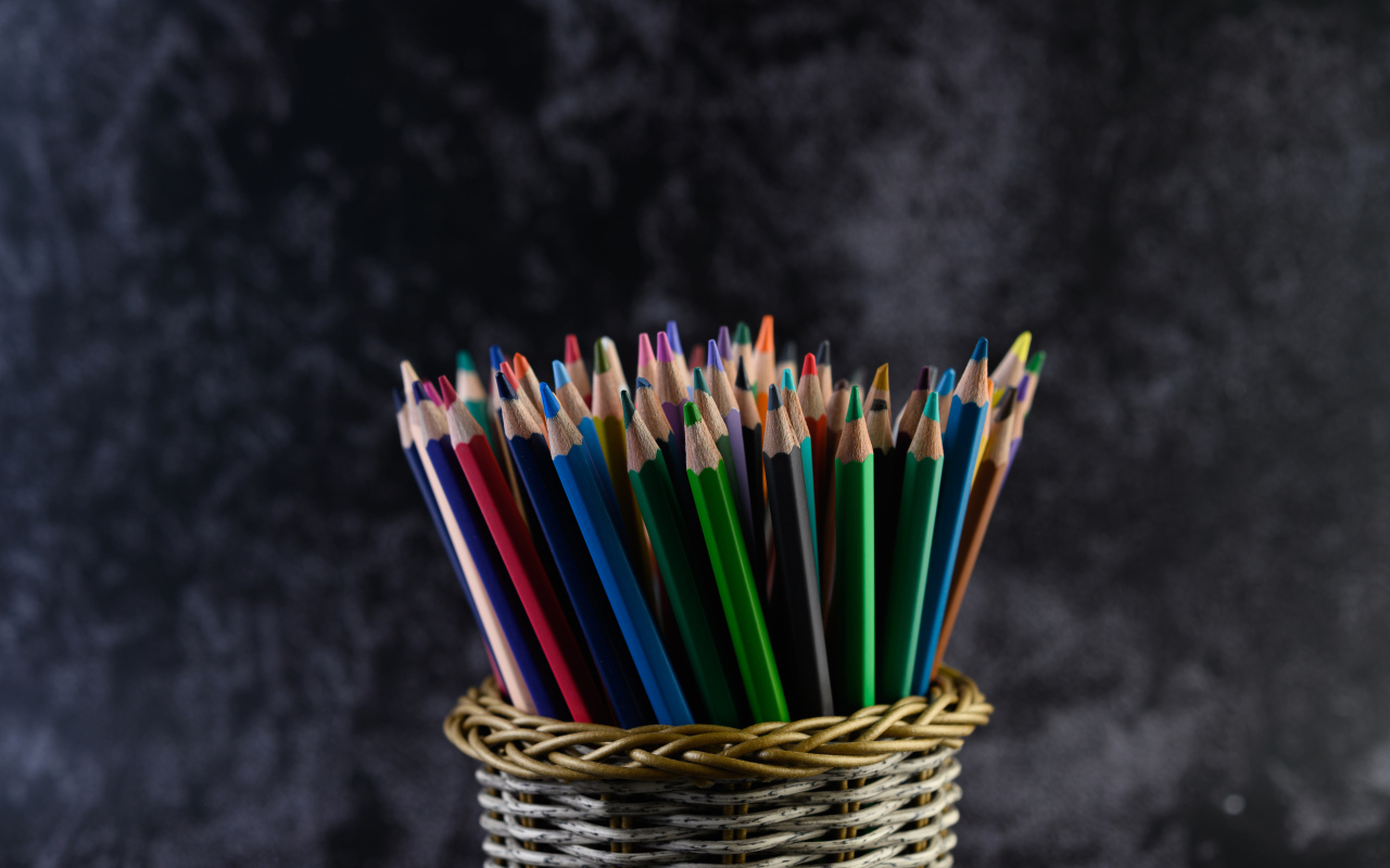 Разноцветные карандаши в стакане на сером фоне