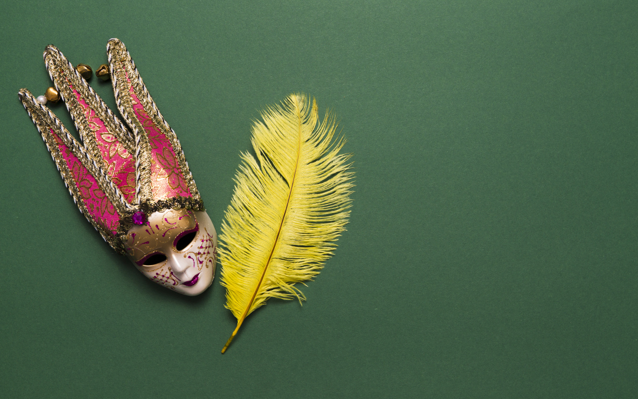 Венецианская маска и желтое перо на зеленом фоне
