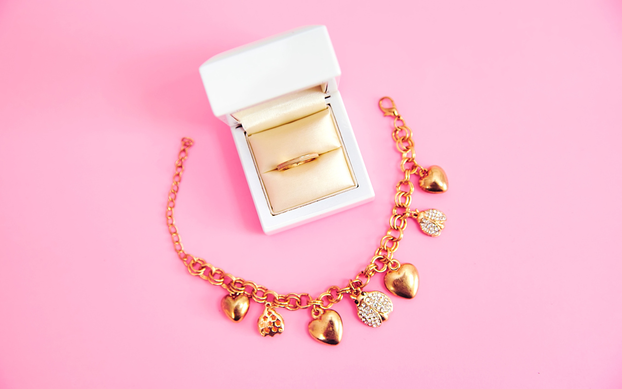 Браслет и кольцо в коробке на розовом фоне