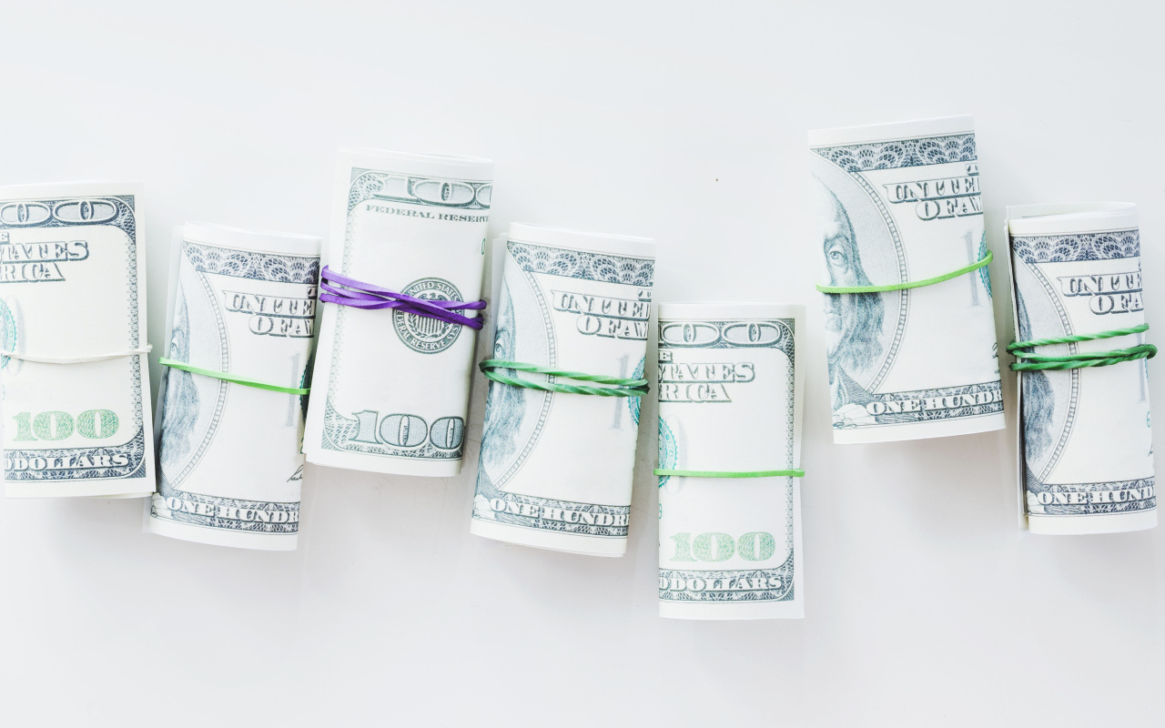 Свертки с долларами на сером фоне