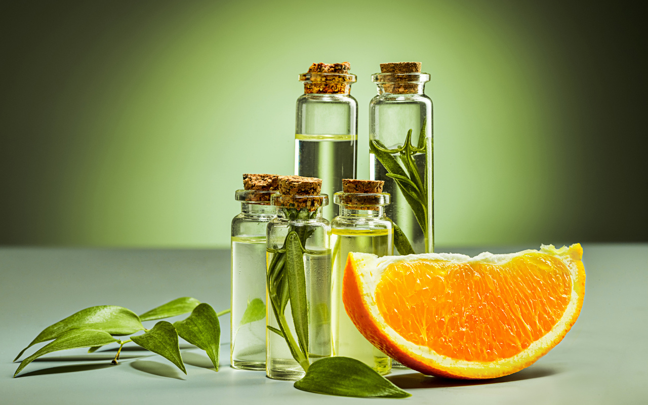 Апельсиновое масло на зеленом фоне с апельсинами