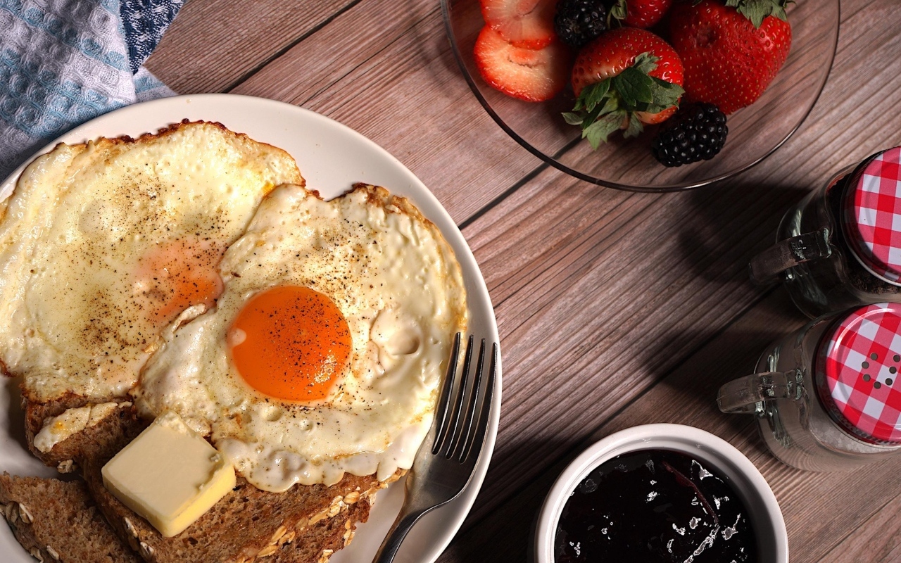 Яичница с гренками на столе с клубникой