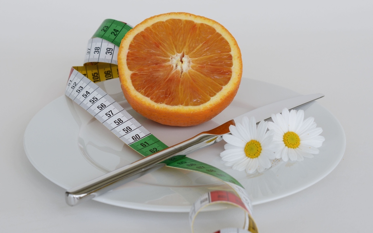 Половина апельсина на тарелке с сантиметром