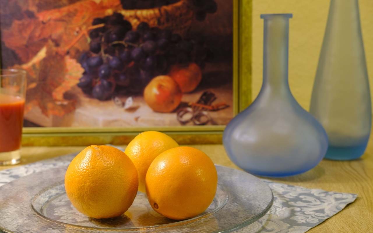 Три апельсина с вазами на столе