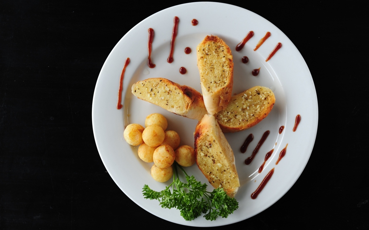 Чесночный хлеб на тарелке с картофельными шариками