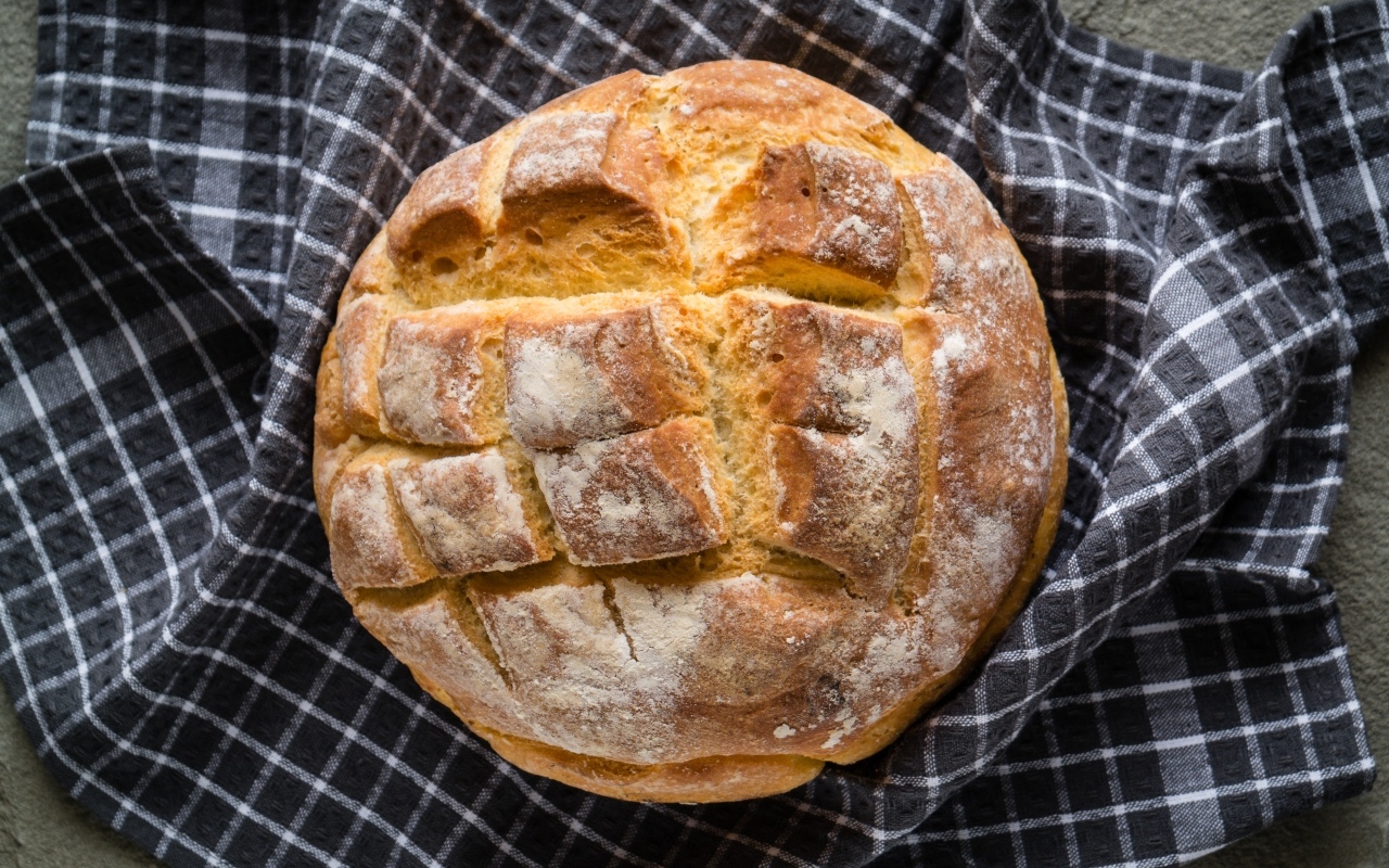 Круглый хрустящий хлеб на столе со скатертью