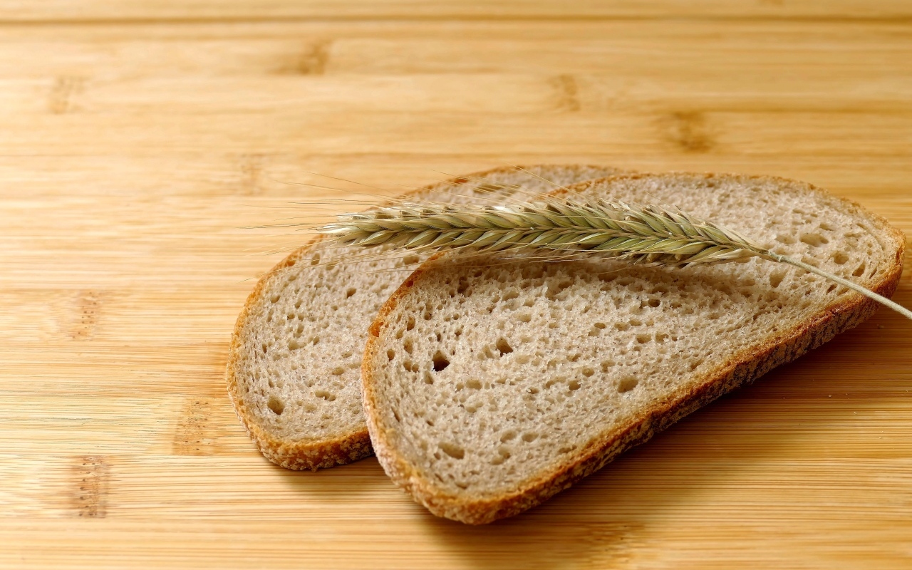 Два куска хлеба с колоском на деревянном столе