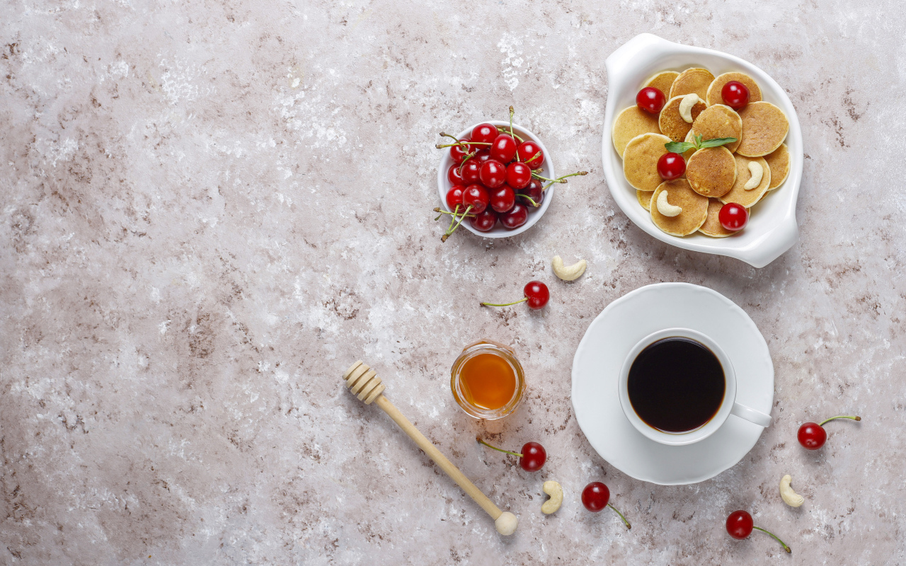 Оладьи на столе с вишней, кофе и медом