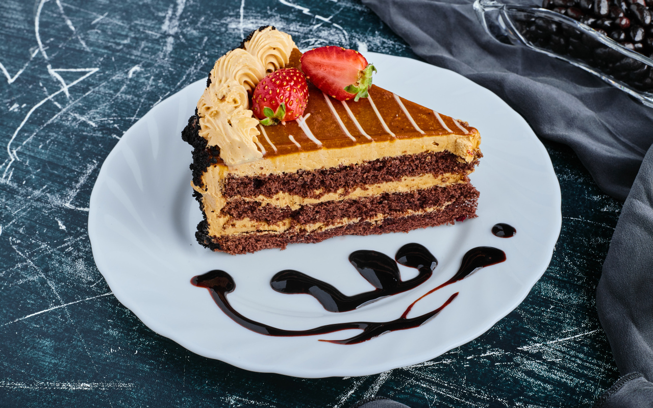 Кусок торта с клубникой на большой белой тарелке