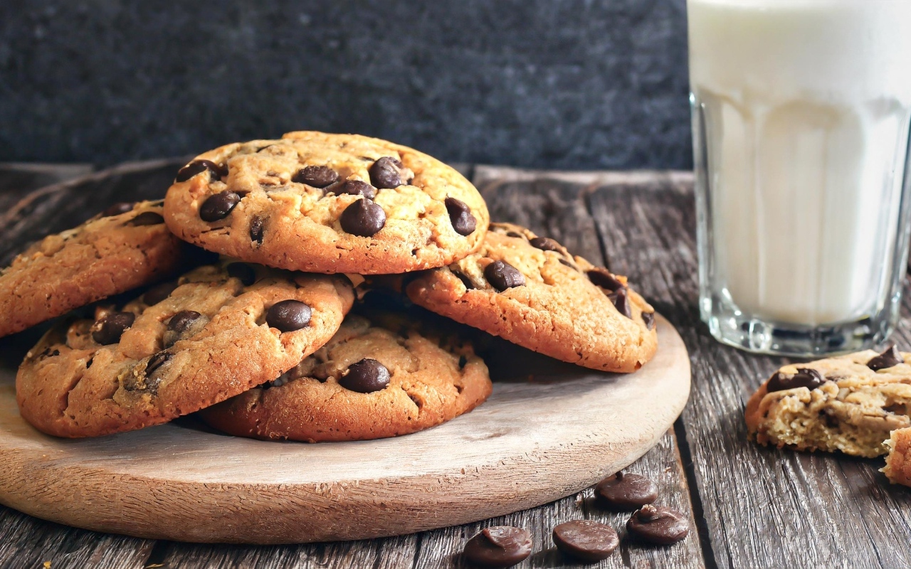 Круглое печенье с шоколадом на столе со стаканом молока