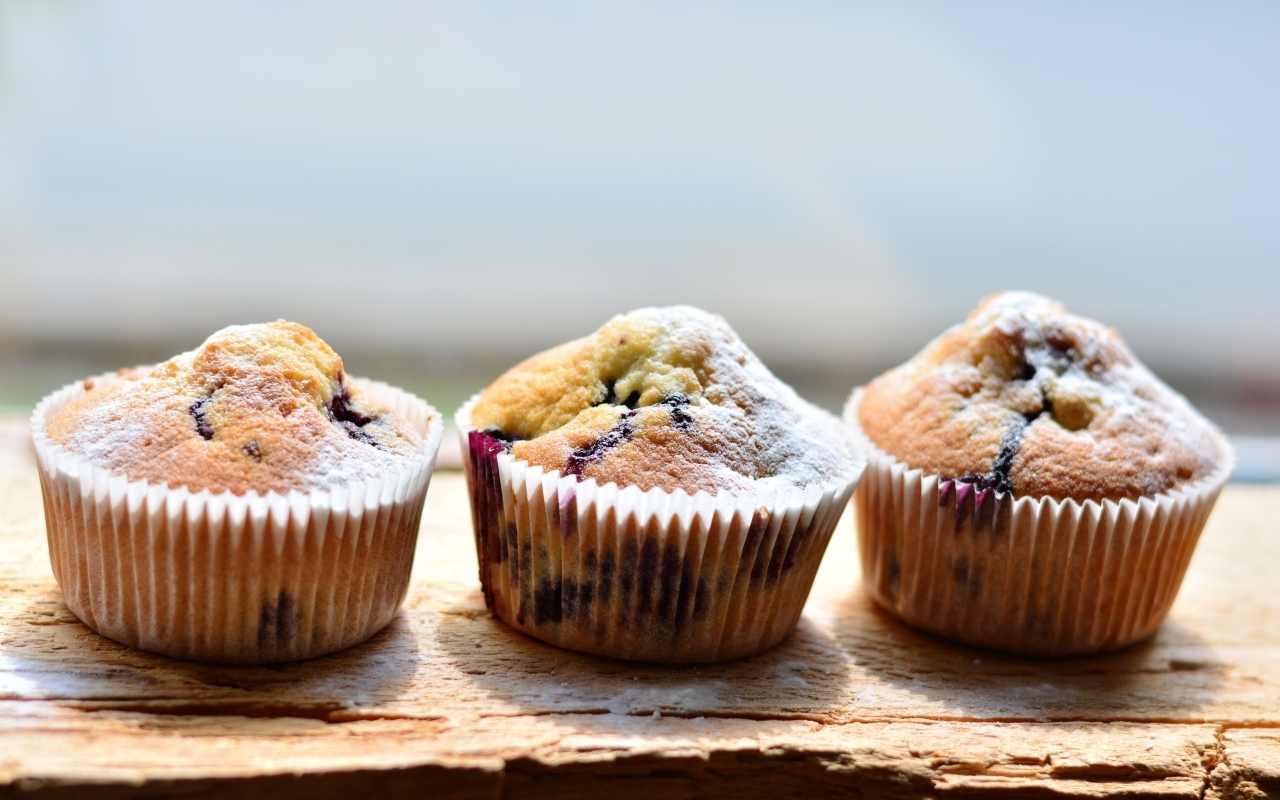 Три вкусных сладких кекса с сахарной пудрой на столе