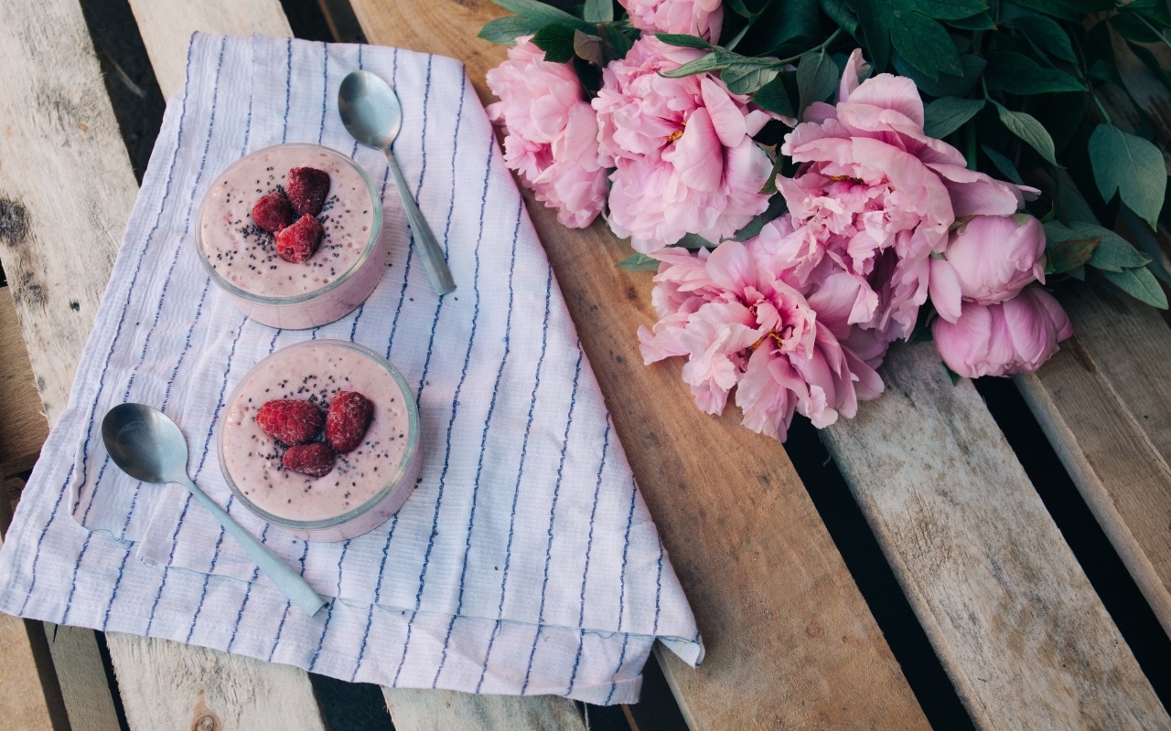 Два стакана с десертом на лавке с букетом пионов