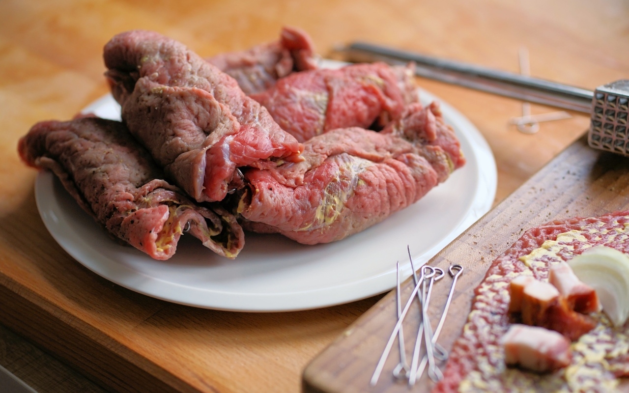 Рулетики из свинины на большой белой тарелке