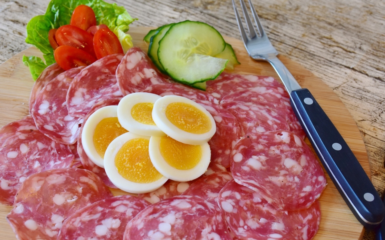 Колбаса салями на доске с вареными яйцами и овощами