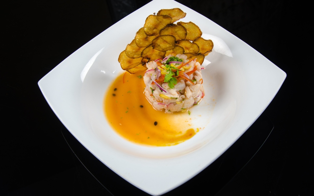 Морепродукты с соусом на большой белой тарелке на черном фоне