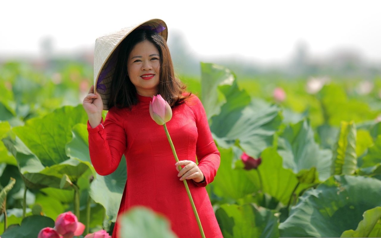 Девушка азиатка в красном платье у цветов лотоса