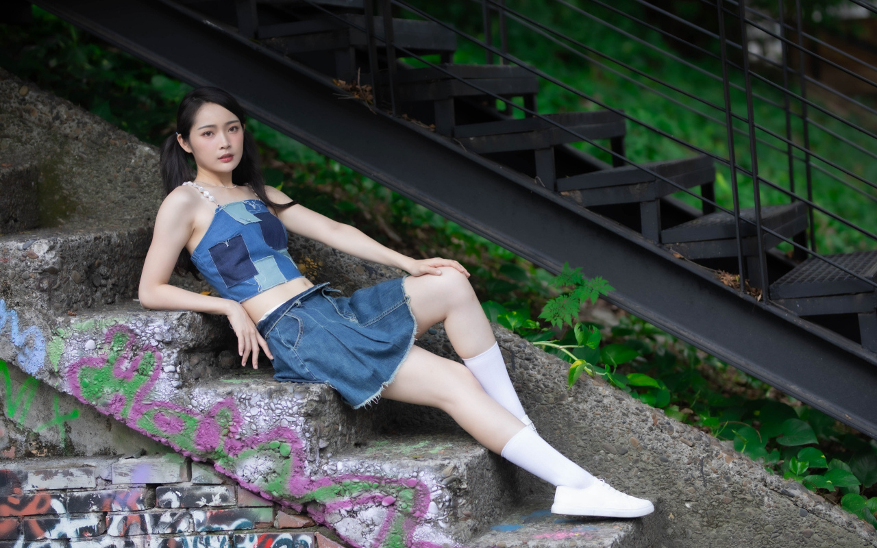 Девушка азиатка в юбке лежит на лестнице