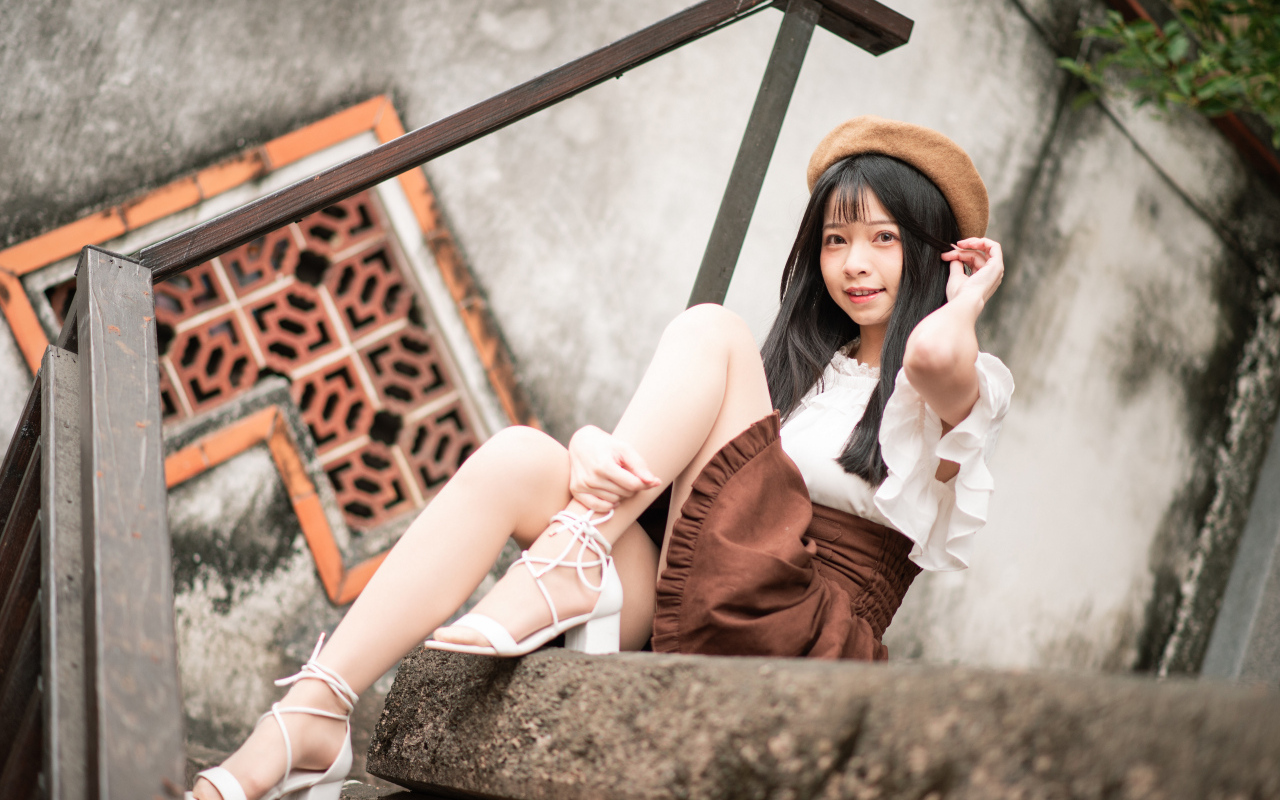 Девушка азиатка в белых туфлях сидит на ступеньках