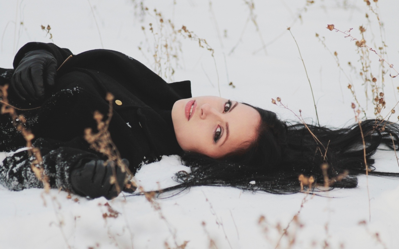 Красивая брюнетка лежит на холодном снегу