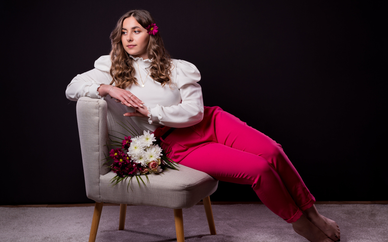 Милая девушка сидит на сером кресле с цветами