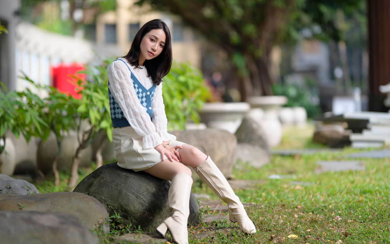 Милая девушка сидит на камне в парке