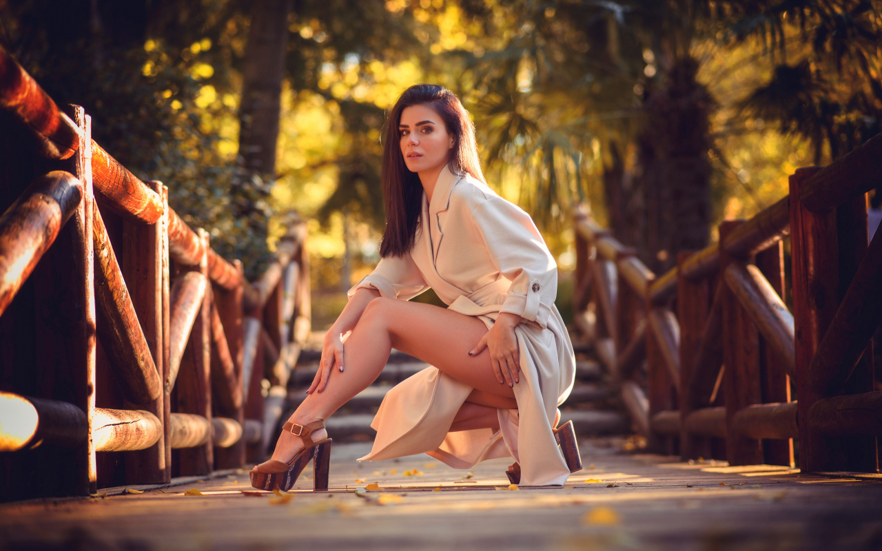 Девушка в пальто на мосту в парке 