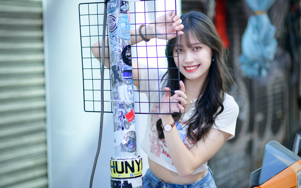 Улыбающаяся азиатка держится за сетку